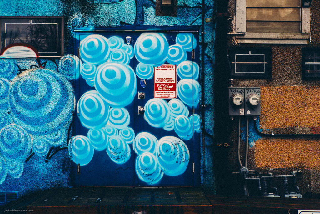 Vibrant blue circular street art on a door in Vancouver's Commercial Drive, captured with a Leica M-D (Typ 262) and Canon 50mm f/1.4 LTM lens.