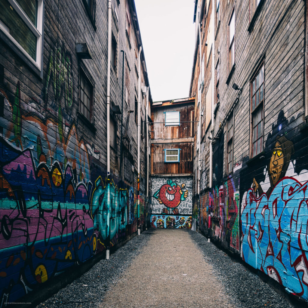 Vibrant graffiti art adorning the walls of an alleyway with rustic wooden staircases in Vancouver."