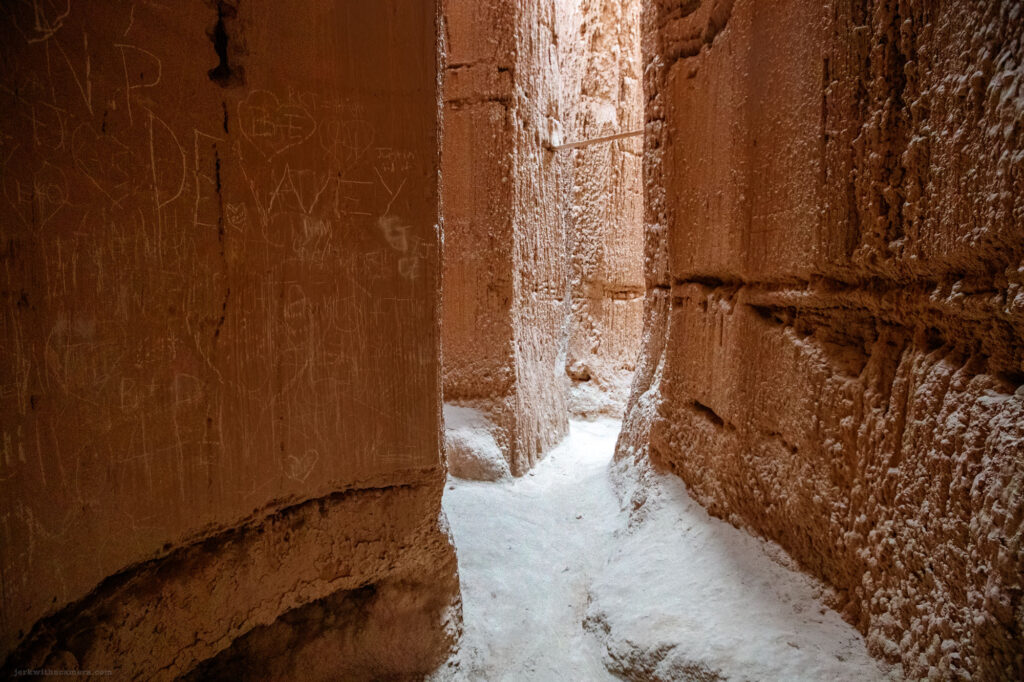 Looking up through towering rock formations with vivid blue sky above, illuminated by the warm glow of sunlight.