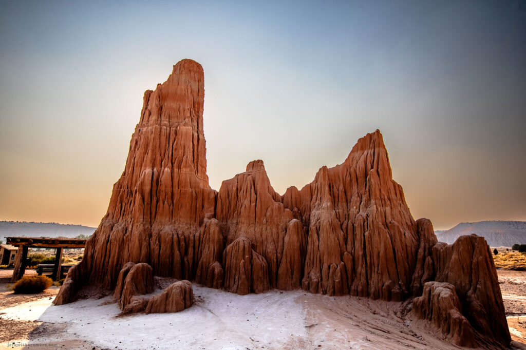 Looking up through towering rock formations with vivid blue sky above, illuminated by the warm glow of sunlight.