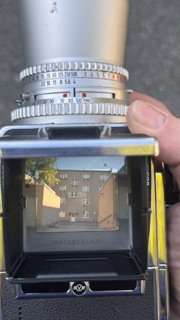 View through a Hasselblad camera viewfinder showing an apartment building.