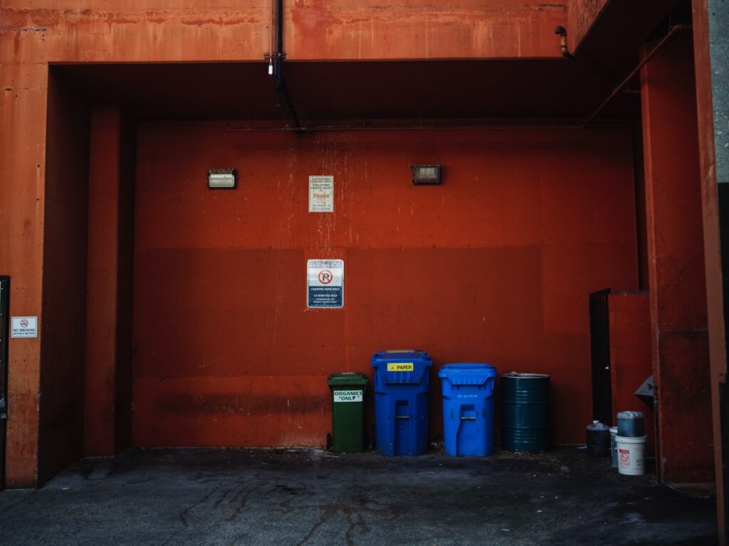 Orange wall with garbage bins lined against it.