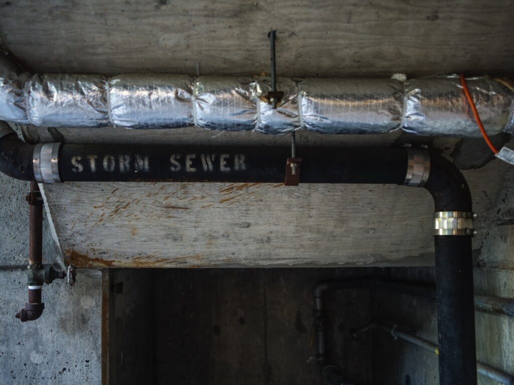 Pipes labeled “Storm Sewer” under a concrete ceiling.