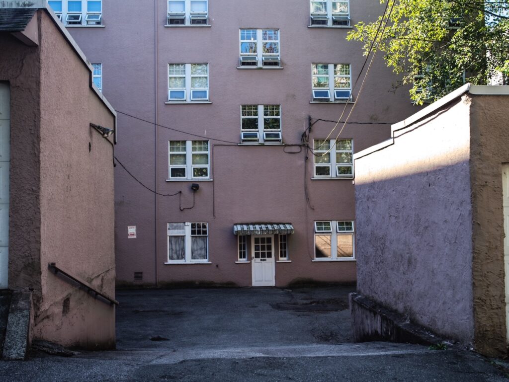 Apartment building with multiple windows viewed from an alley.