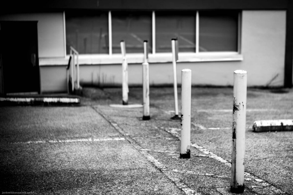 White parking lot bollards in a row in front of a building with large windows